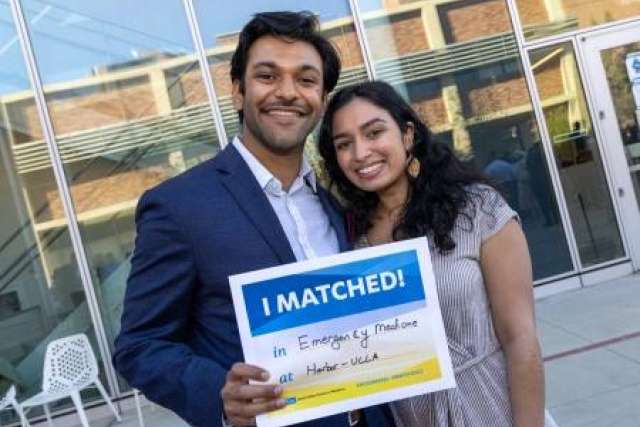  Vivek Shah and Siri Lasya Rallabhandi smile, holding a sign that reads "I MATCHED!" in front of a modern building.