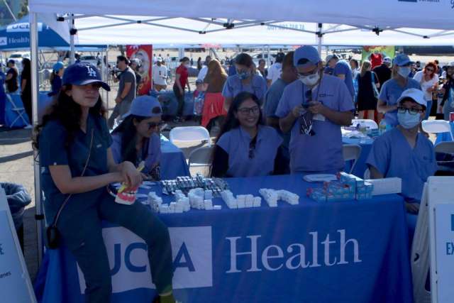 Fam Care Village booth with staff behind UCLA Health table at outdoor community fair