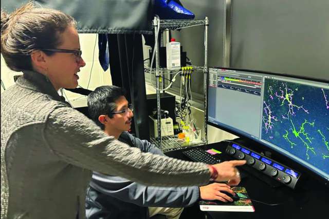 Two people at a lab computer pointing at screens showing molecular models