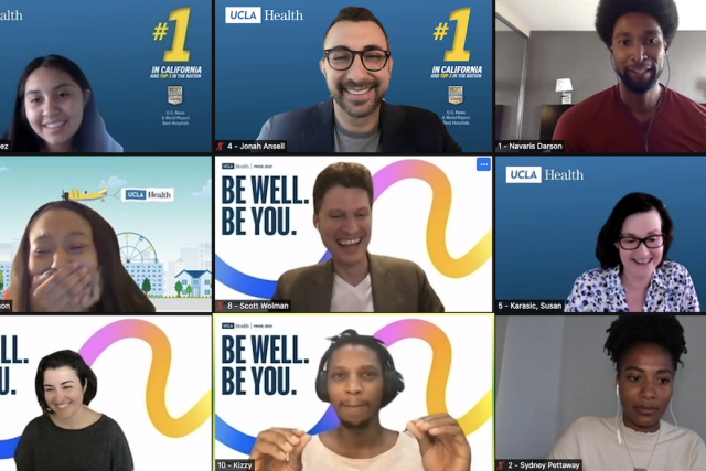  A grid of nine smiling people in a video conference call, with several having "UCLA Health" and "BE WELL. BE YOU." virtual backgrounds.
