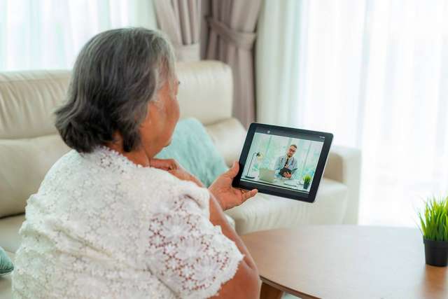 Elderly woman on iPad with doctor, seated and holding tablet