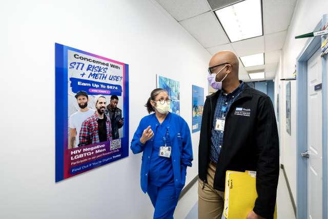 Clinical researcher Christopher Blades and laboratory coordinator Demetria Villanueva walk down a hallway of the Vine Street Clinic.