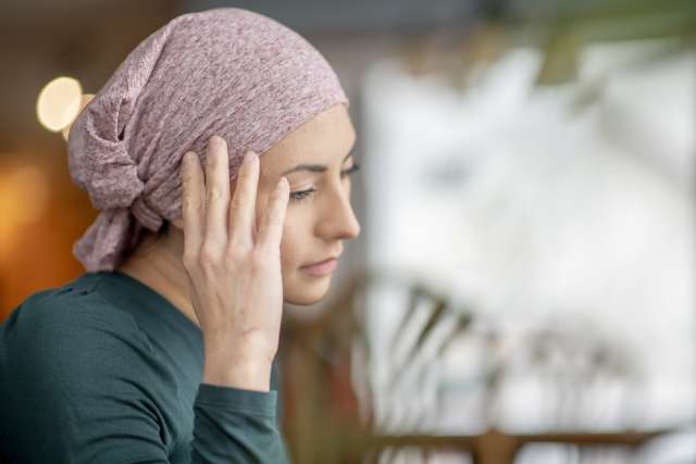 Woman wearing a headscarf touching her ear and looking downward