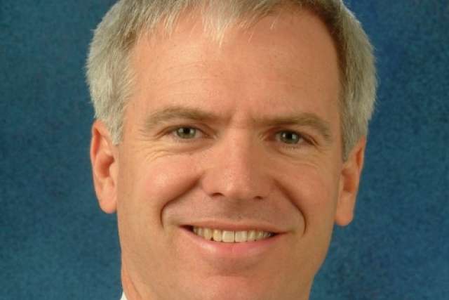 Dr. John Fitzgerald smiling headshot against blue background