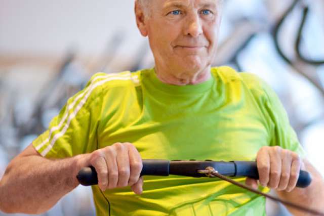 Older man exercising on a rowing machine in gym