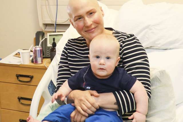 Robin Reader in hospital bed holding a baby