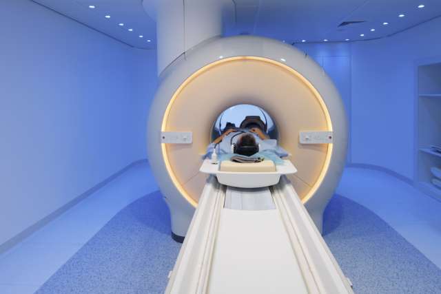 Patient supine with head inside a circular MRI scanner on a sliding table.