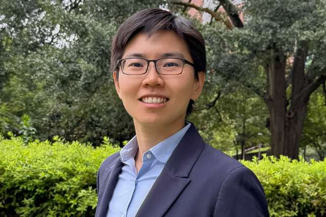 Cancer researcher Fang-Yi (Ida) Su, standing in front of a garden and looking at the camera and smiling