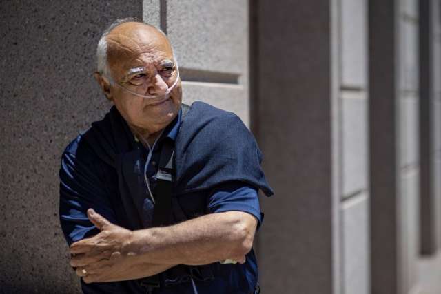 Marcelo Olavarria in a navy shirt leans against a stone wall, arms crossed.