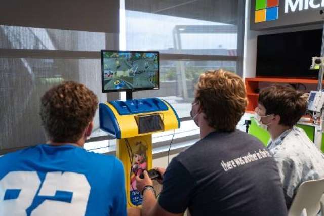 Three people seated playing on a TV screen