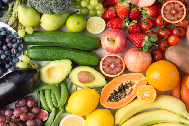 Fruits and vegetables on a table displayed in the colors of the rainbow