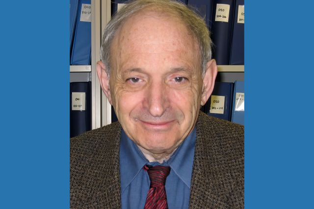 Headshot of esteemed cancer researcher Dr. Robert Elashoff, wearing a dark gray suit, blue button up shirt and a red tie.