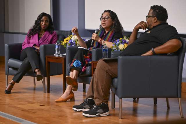 Dr. Medell Briggs Malonson, on stage, left, moderates a panel discussion with Cynthia Gonzalez, PhD, an assistant professor at Charles R. Drew University of Medicine and Science, and Derek Steele, executive director of the Social Justice Learning Institute.