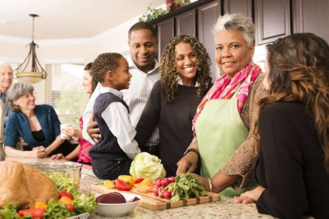 Family gathering in a kitchen, sharing food, and enjoying each other's company.