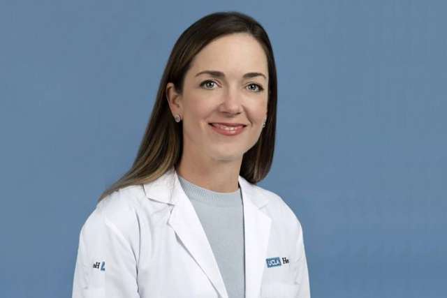 A person wearing a lab coat against a blue background.
