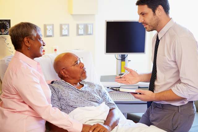 A doctor speaks with a patient and his caregiver at the hospital.