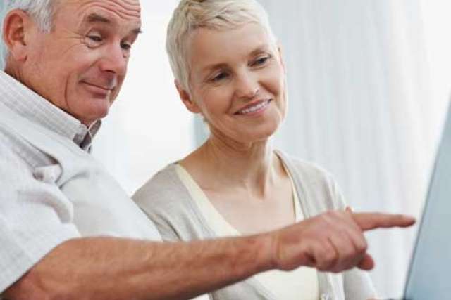 Two people sitting together, one pointing at a computer screen.