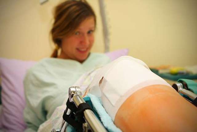 Patient with ACL-tear in hospital bed showing bandaged knee and brace