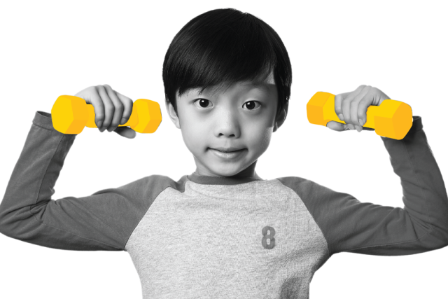 A young boy, in black and white, holds a yellow dumbbell in each hand, flexing his biceps and smiling at the camera.