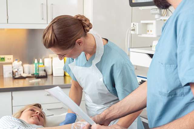 Patient on exam table while medical staff prepare colonoscopy