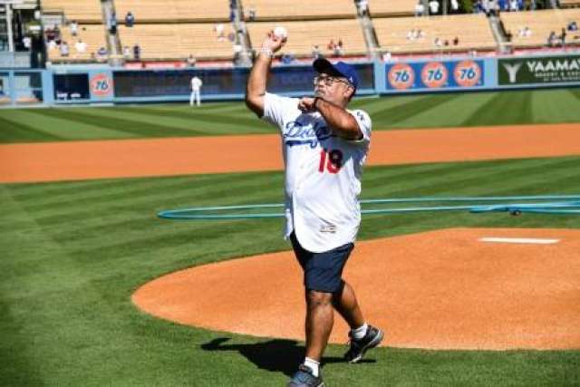 Santiago Munoz III, in a Dodgers jersey and cap, prepares to throw a baseball on the pitcher's mound of a stadium.