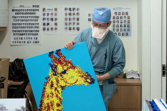 Dr. Zhuang T. Fang shows a medicine cap mosaic created by nurses Cody Kaufman and Joanna Franco-Perez. (Photo by Joshua Sudock/UCLA Health)