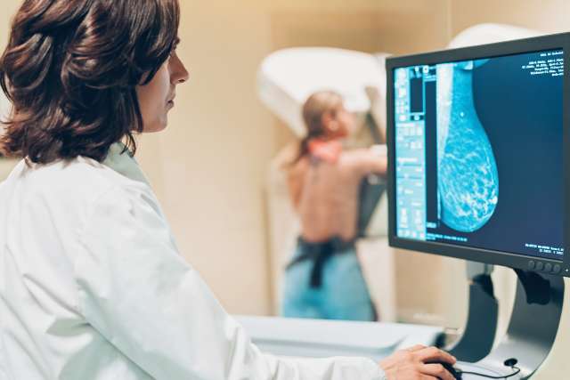 A doctor performs a breast exam with a patient