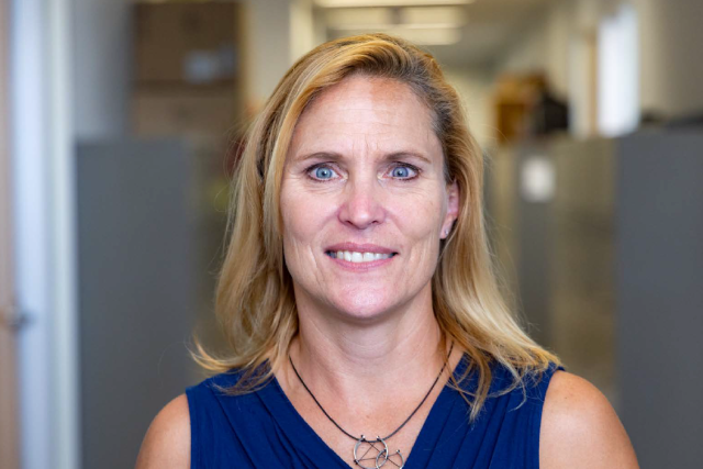 Dr. Sheila Stewart, headshot: smiling woman in blue top in an office.