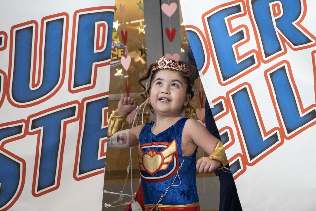 Pediatric patient Stella crashes through the banner at her superhero-reveal party