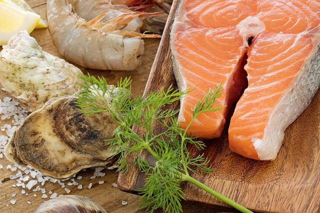 Seafood on a counter including a salmon filet, oysters, and shrimp.
