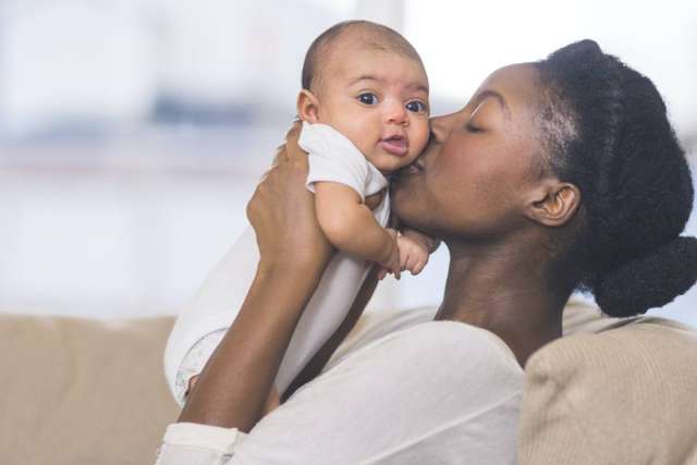 Close-up showing a woman kissing her baby, highlighting the loving connection between them