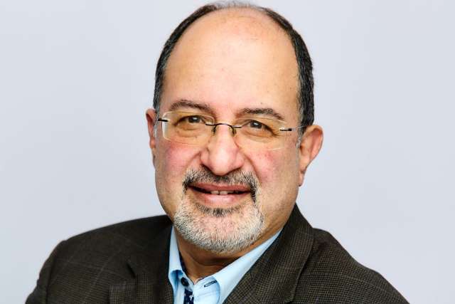 Professional portrait of Dr. Arash Naeim, smiling and wearing a suit and tie