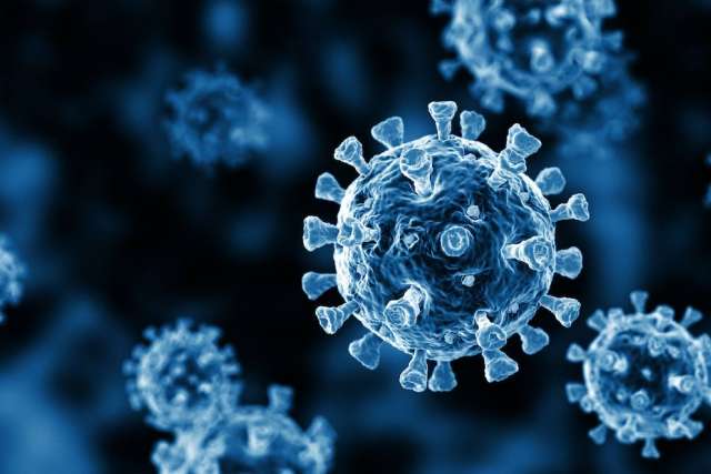 A 3D illustration of several SARS-CoV-2 (COVID-19) virus particles in various stages of focus, rendered in deep blue tones against a dark background.