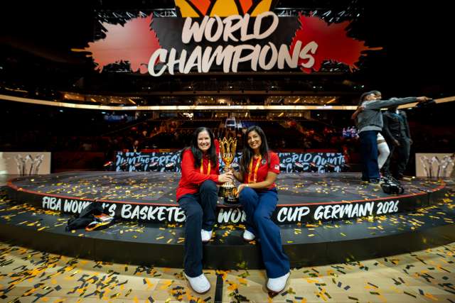 Two women hold a trophy in front of a World Champions sign.
