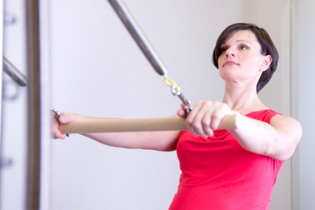 A female patient, wearing a red shirt, doing physical therapy exercises.