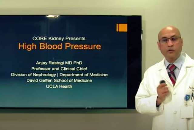 Doctor in a white coat presenting on high blood pressure in front of a screen.