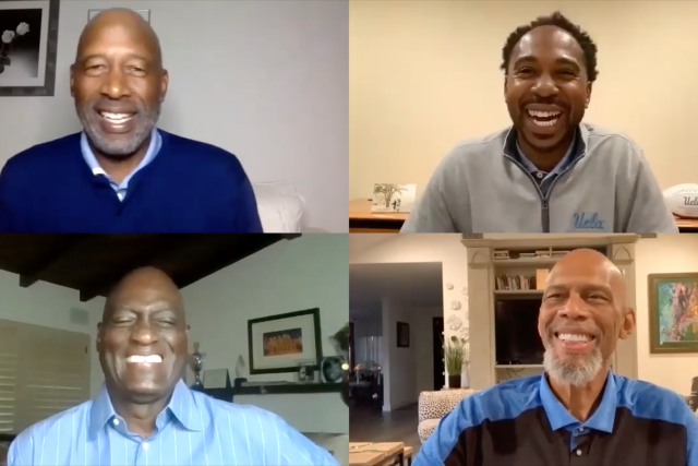 A video conference screenshot of four smiling men, including Kareem Abdul-Jabbar, Michael Cooper, and James Worthy. Two of the men wear blue shirts.