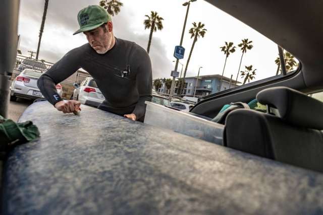 Dr. Sassoon waxing his surfboard in the back of a car