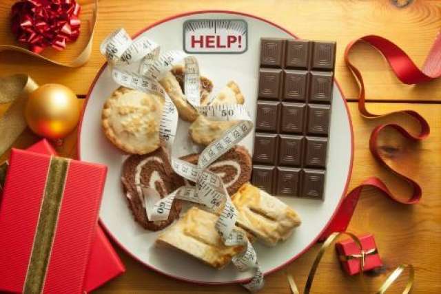 Plate with pastries and chocolate wrapped in measuring tape, “HELP!” text on a scale, surrounded by gifts and ribbons.