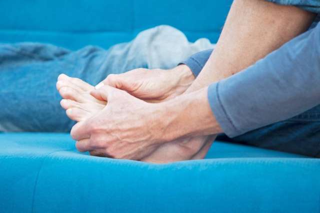 Hands holding bare feet on blue sofa
