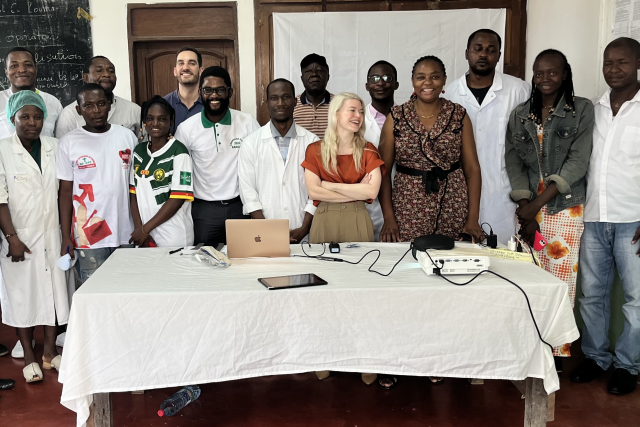 A group of doctors poses for a photo behind a table.