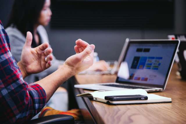 A man gestures his hands during a work meeting with colleagues.