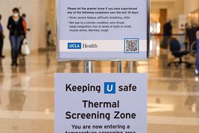Sign at UCLA Health marking a thermal screening zone for temperature checks and COVID-19 symptom reporting.