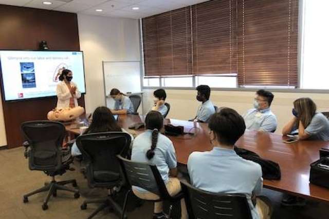 Allied Health students engaged in a presentation around a conference table.