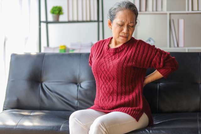 Woman sitting on a couch with back pain