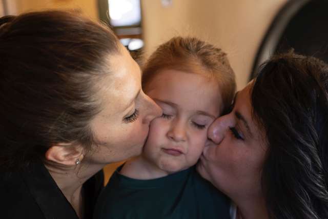 Sophia is kissed on cheeks by her moms