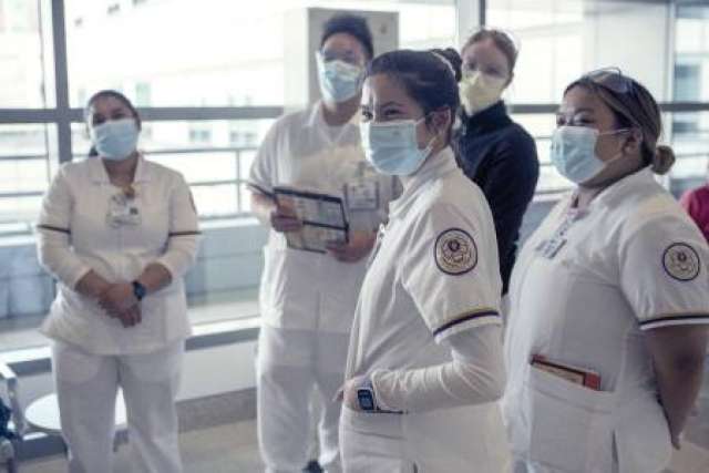 Nurses wearing white uniforms, wearing masks standing inside of Ronald Reagan UCLA Medical Center