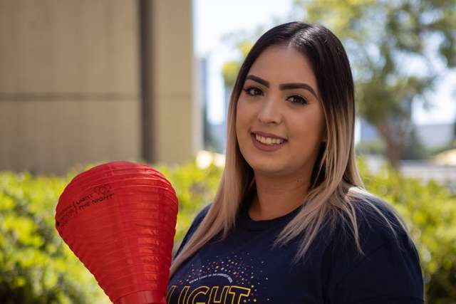 Daisy Cazares smiling outdoors holding a red paper lantern.