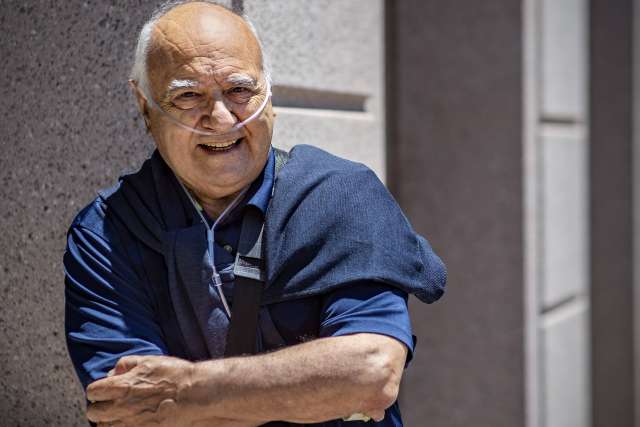 Marcelo Olavarria in a blue shirt and sweater, leaning against a wall outdoors.