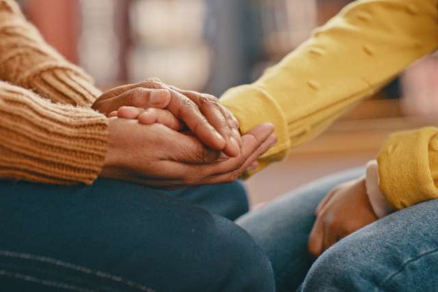 A caregiver holds a person's hand.